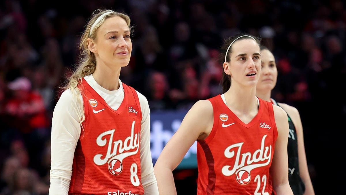Indiana Fever guard Sophie Cunningham and guard Caitlin Clark standing next to each other on basketball court