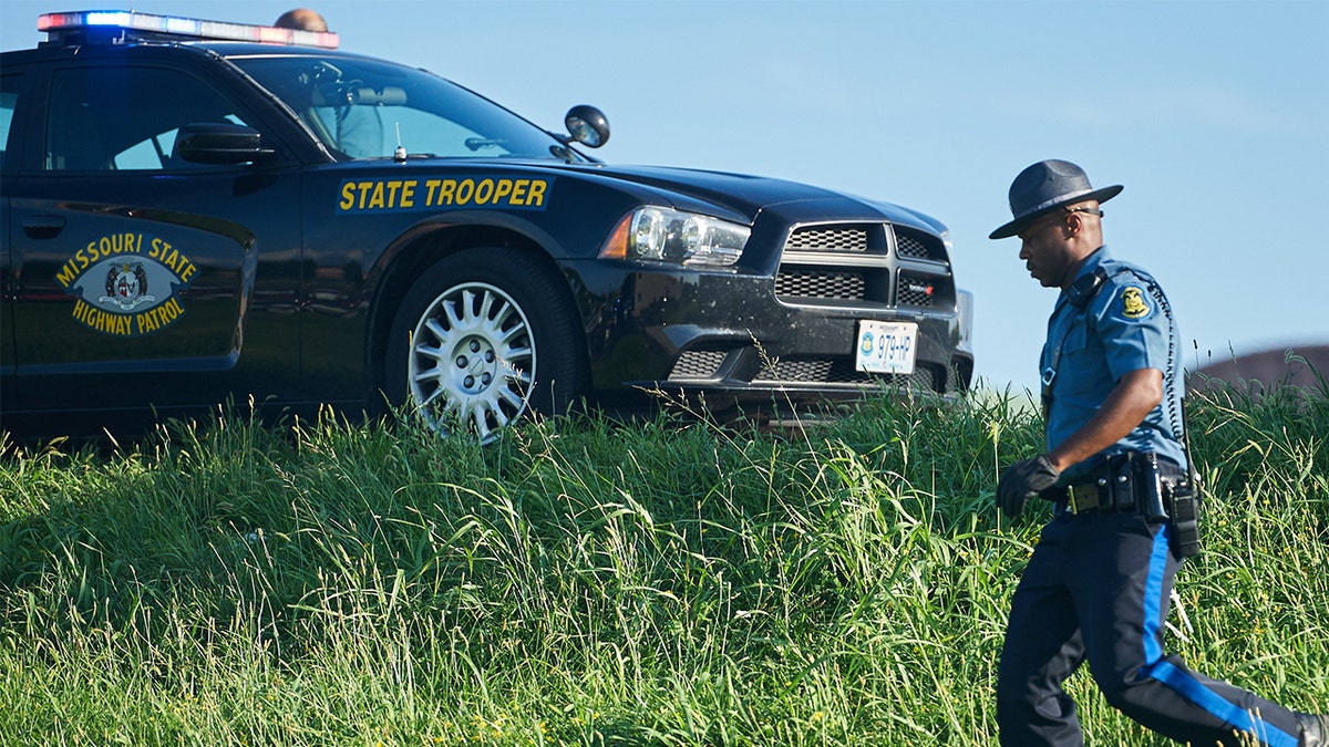 trooper near car on highway shoulder