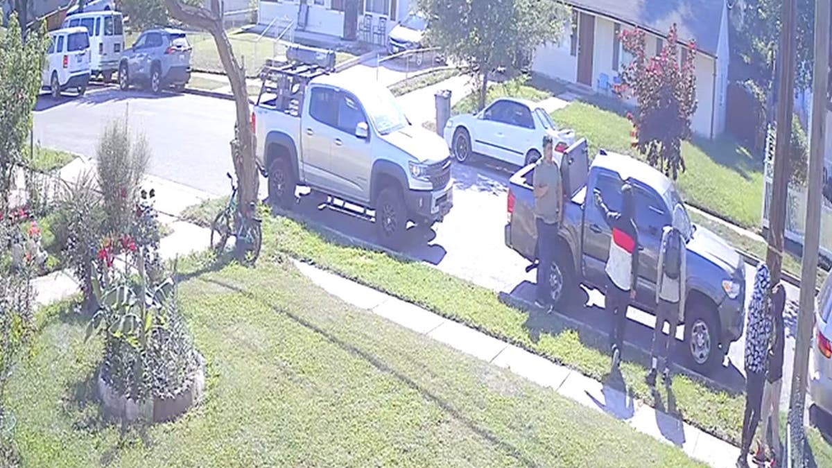surveillance video still image of a hooded teen pointing a gun at the vicitm