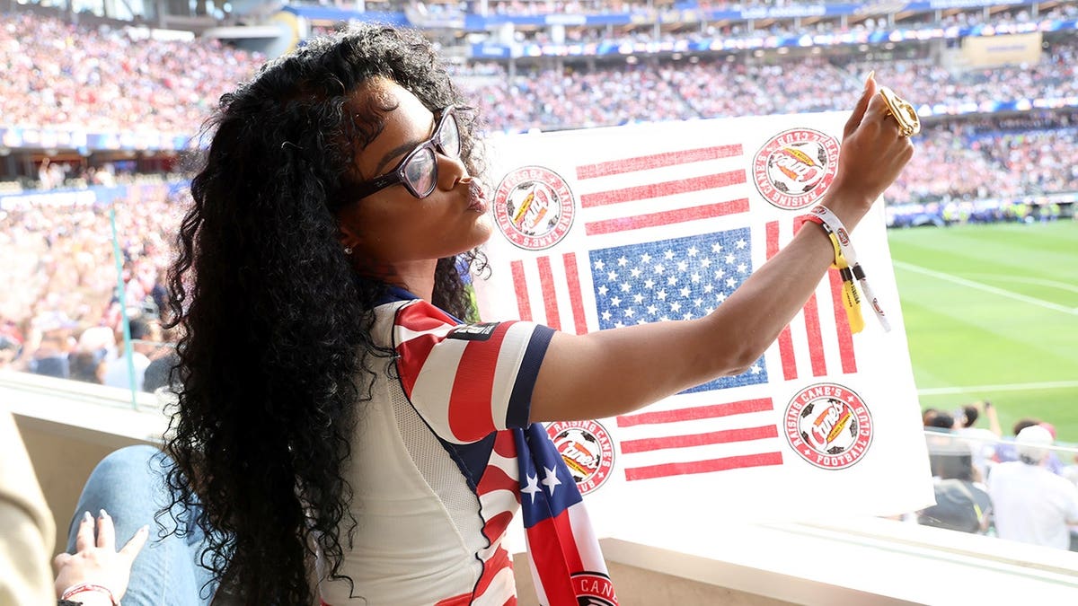 Teyona Taylor segura uma bandeira enquanto assiste ao jogo EUA x Paraguai em Los Angeles.