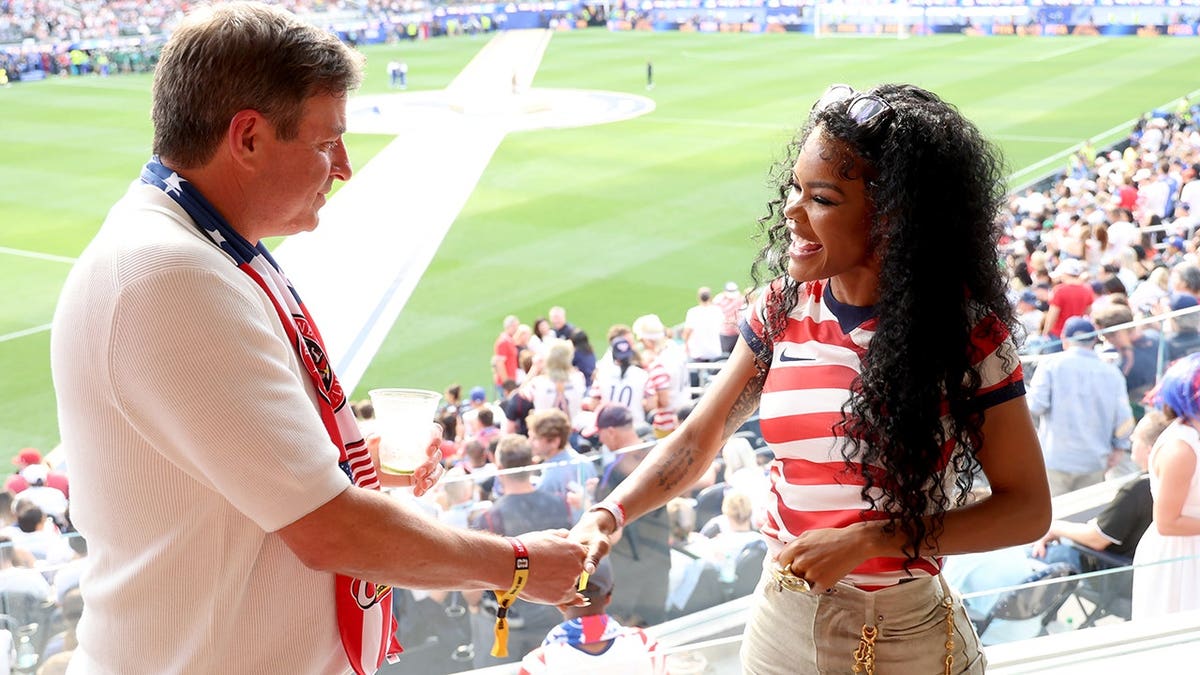 Teyona Taylor e o dono do Raisin' Cane, Todd Graves, apertando as mãos durante a partida entre EUA e Paraguai na Copa do Mundo.