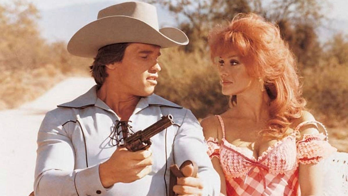 Arnold Schwarzenegger and Ann-Margret pose for a promotional photo for the movie The Villain.