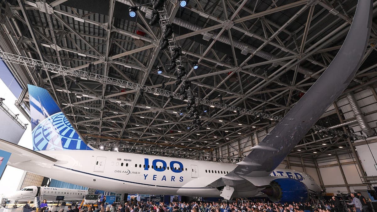 Um avião da United com pessoas cercando-o em um hangar.