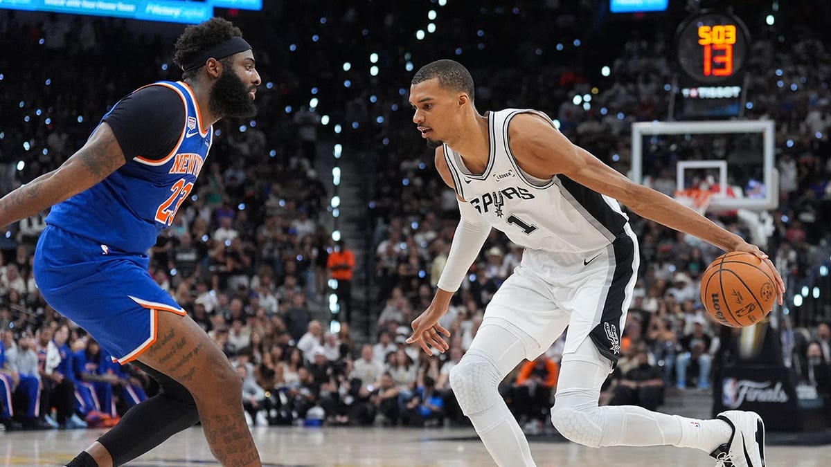 Victor Wembanyama driving with basketball as Mitchell Robinson defends in NBA Finals game