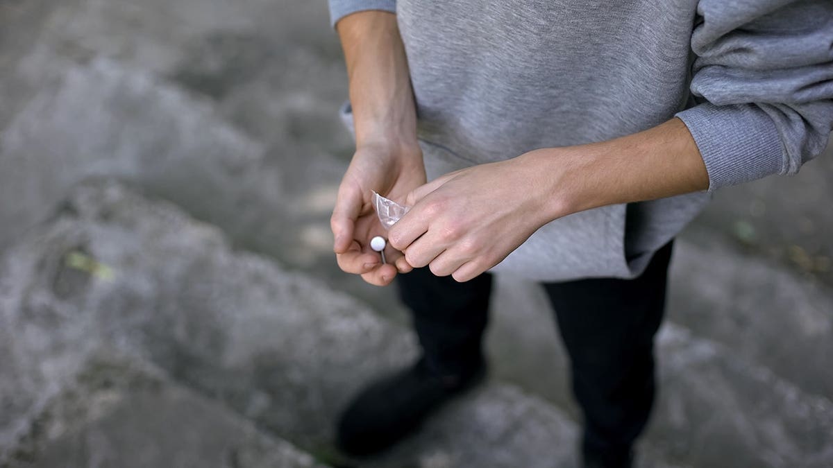 Young man holding and secretly taking narcotic pills.
