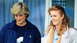 Princess Diana and Sarah Ferguson standing together on a palace balcony looking serious.