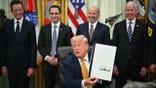 US President Donald Trump holds a singed executive order about quantum computing in the Oval Office
