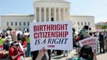 Demonstrators holding signs and rallying on the sidewalk outside the U.S. Supreme Court building.
