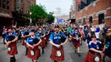Scotland fans wearing kilts and playing bagpipes marching to Fenway Park in Massachusetts