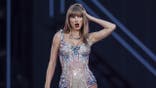 Taylor Swift singing on stage during her Eras Tour in Lisbon
