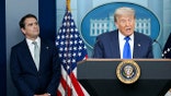 Todd Blanche standing next to President Trump, who is at a podium