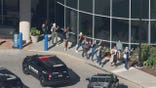 Hospital employees exiting the building with their hands up