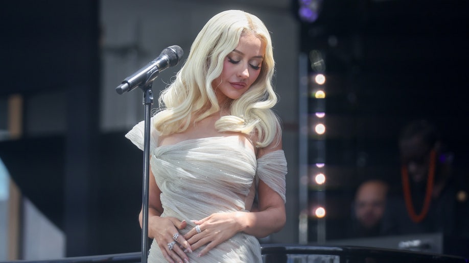 Christina Aguilera stands by a microphone