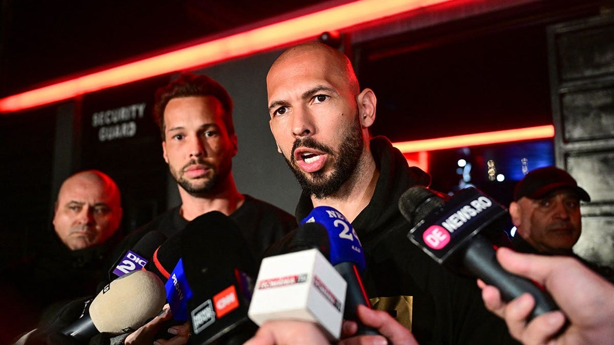 Andrew Tate speaks to the media alongside Tristan Tate in Bucharest.