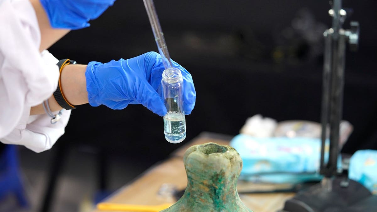 Scientist extracting liquid from bottle