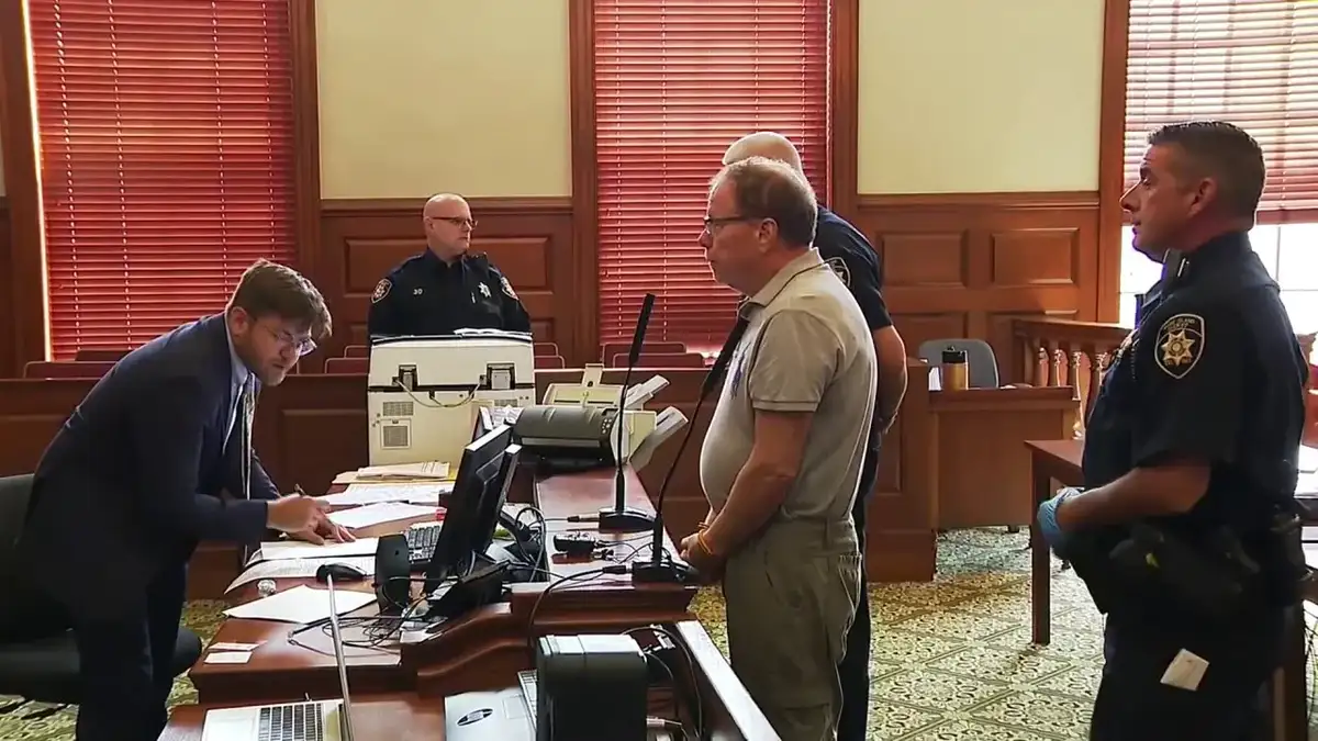 Ronald Fischer stands at the defense table in Newport Superior Court as court personnel and sheriff's deputies look on during his first court appearance since his capture.