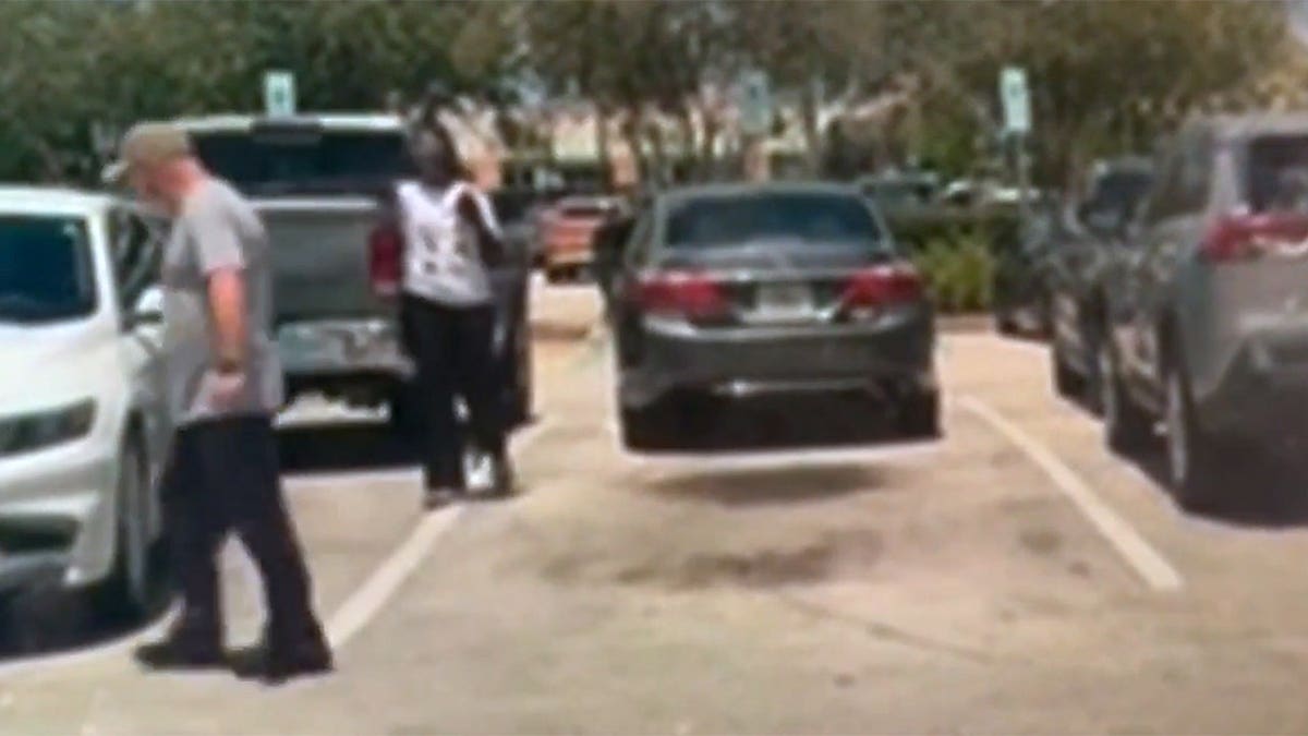 Bart Diguglielmo walks through a Walmart parking lot toward a woman standing near parked vehicles during a confrontation in North Lauderdale, Florida.