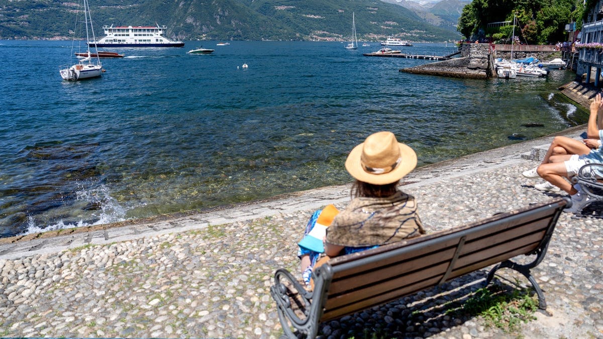 View of tourist in Varenna sitting on bench near water