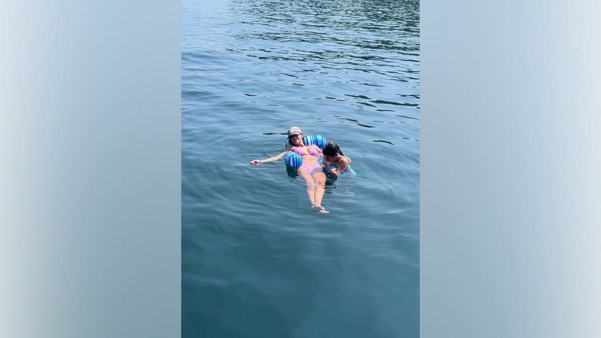 Jana Kramer floats in the lake wearing a pastel pink bikini and a baseball cap while relaxing during a Fourth of July lake getaway.