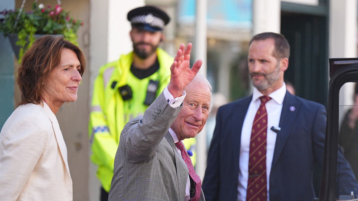 King Charles in a grey suit waving to the public in Scotland.