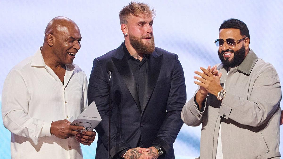 Mike Tyson, Jake Paul and DJ Khaled stand together on stage.