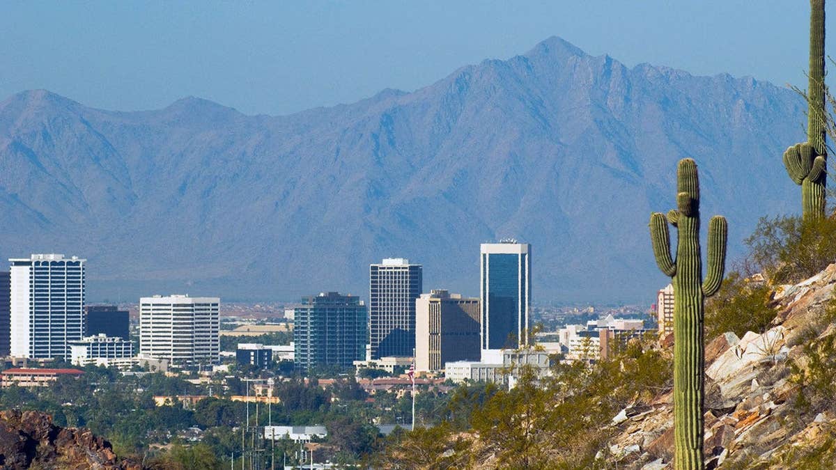 Phoenix skyline with mountains in the background and cactus in the foreground.
