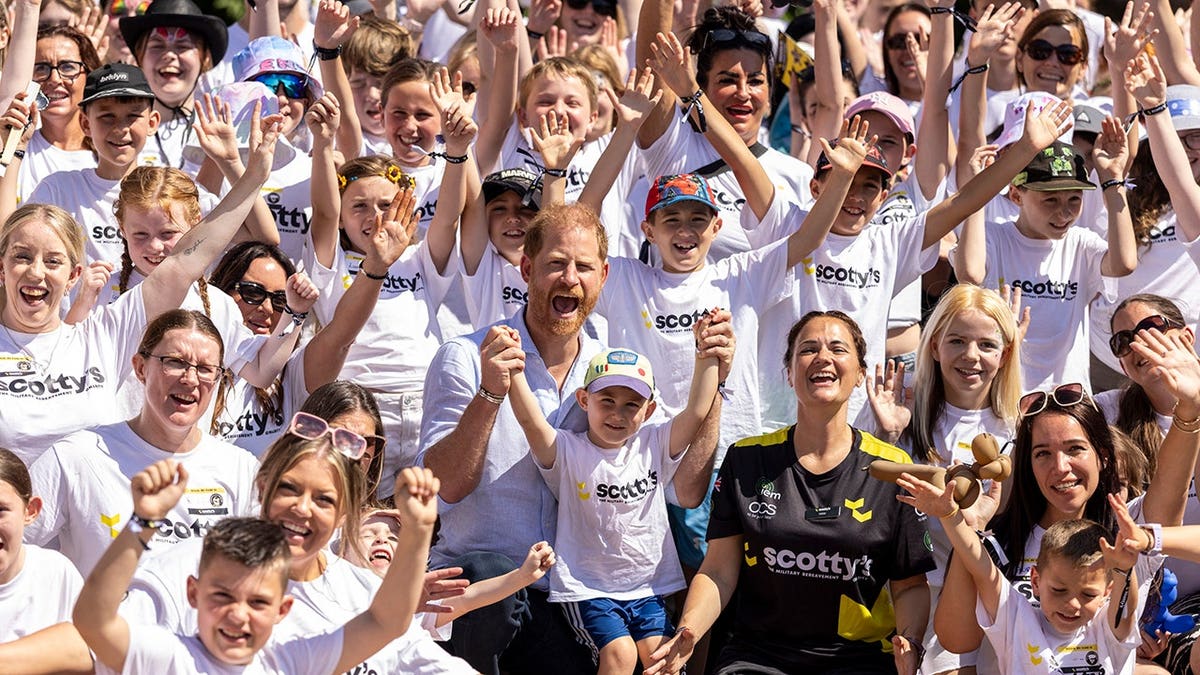 Prince Harry poses with Nikki Scott and River at a festival.