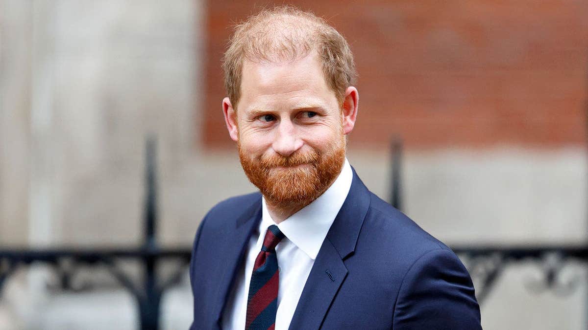 Prince Harry in a dark blue suit walking outside of London's High Court.