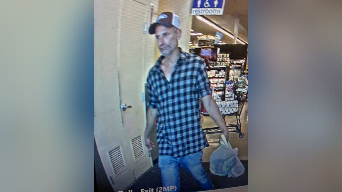 Surveillance image released by the Douglas County Sheriff's Office showing a person of interest walking through a Safeway store while carrying plastic shopping bags during an active residential burglary investigation