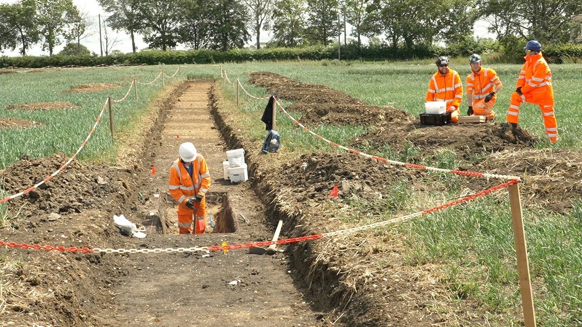 Excavators digging trenches along rail site
