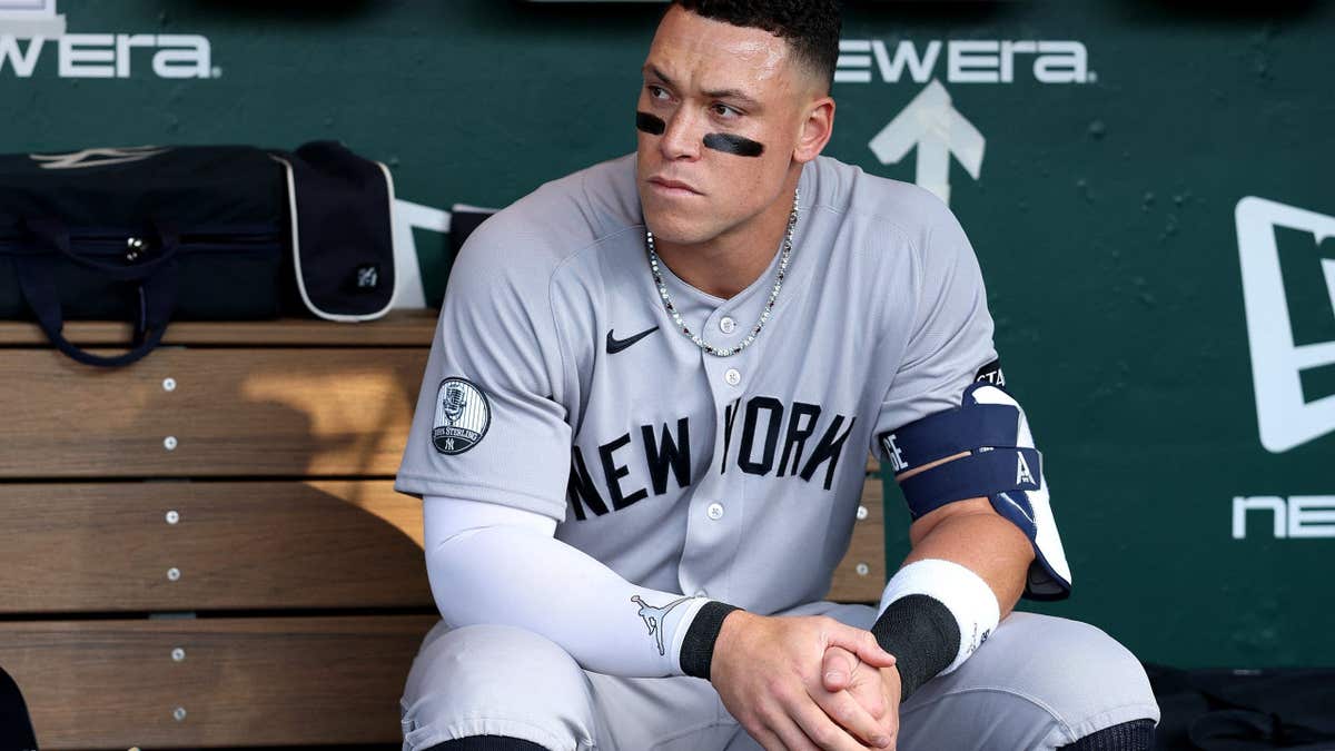 Aaron Judge sitting in the dugout wearing New York Yankees uniform.