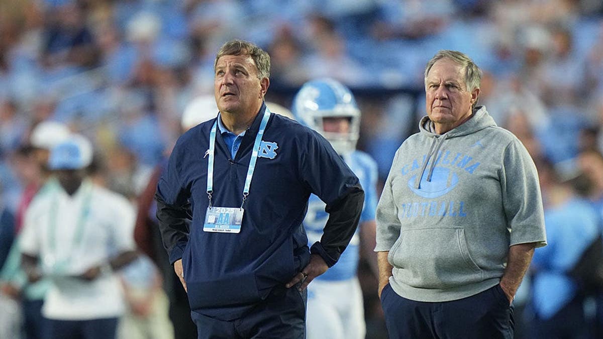 Bill Belichick and Michael Lombardi stand on the sideline