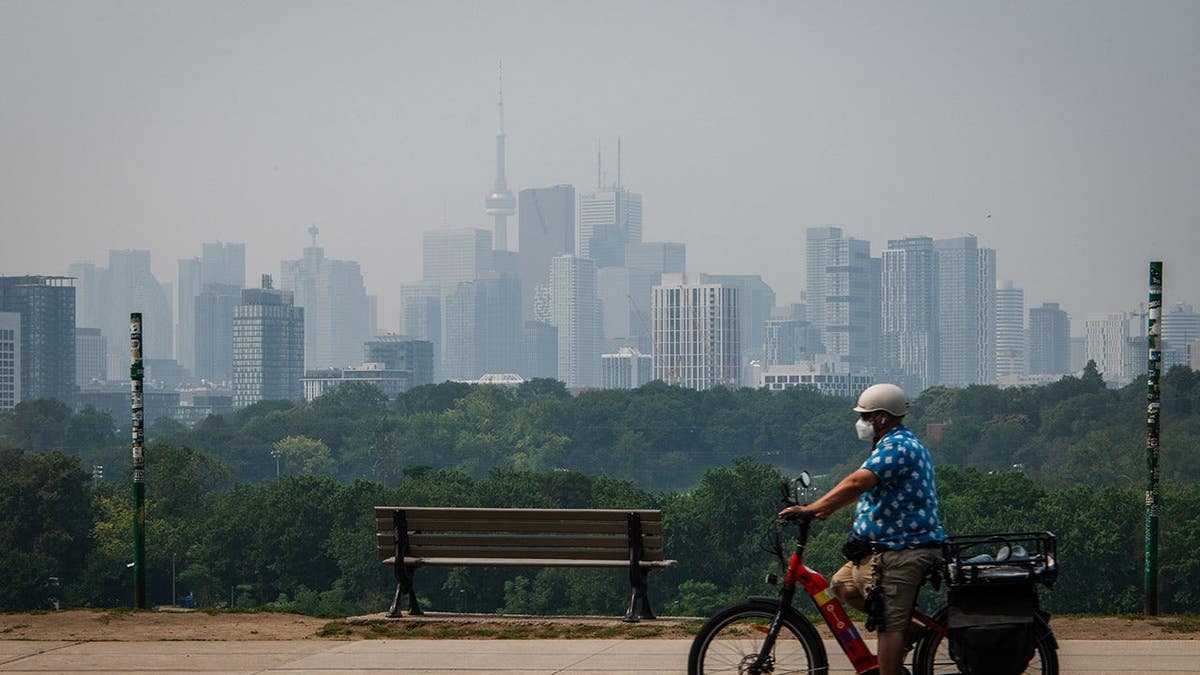 Cyclist wears a mask in smoke-filled Toronto street.