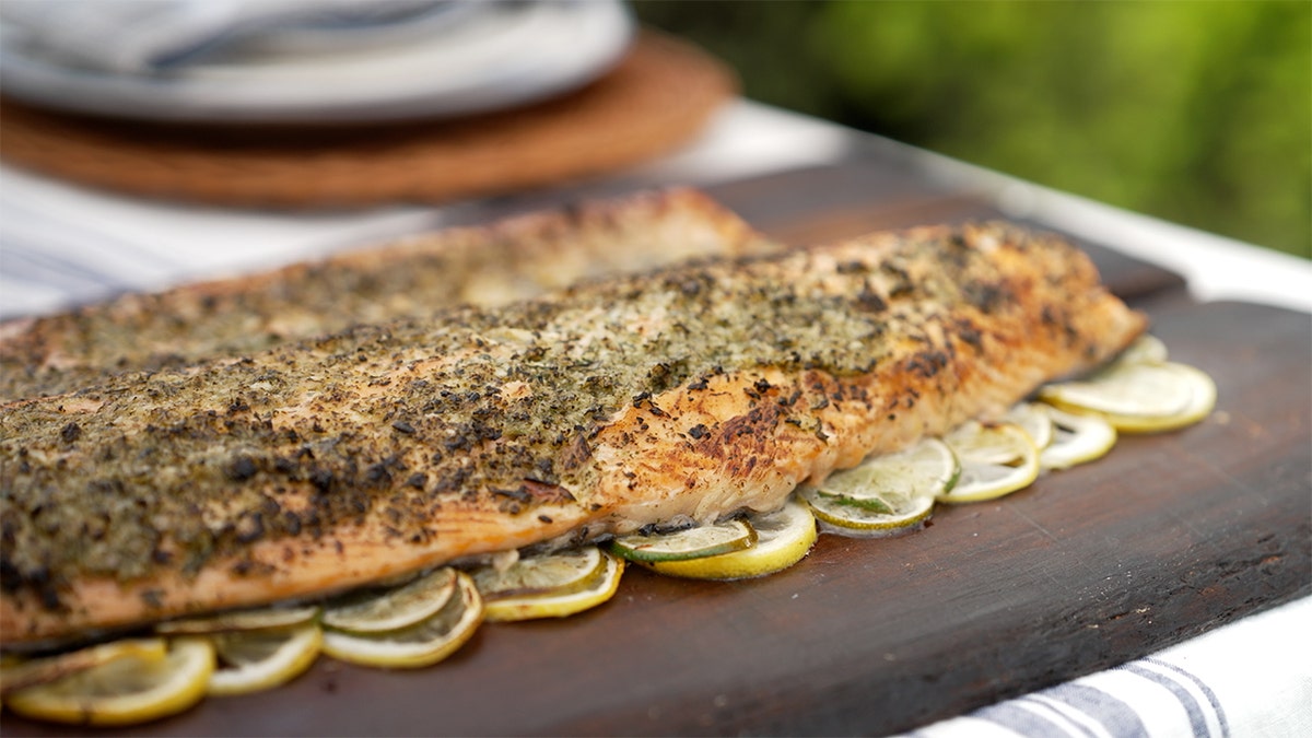Cedar plank salmon on a wooden board with lemons.