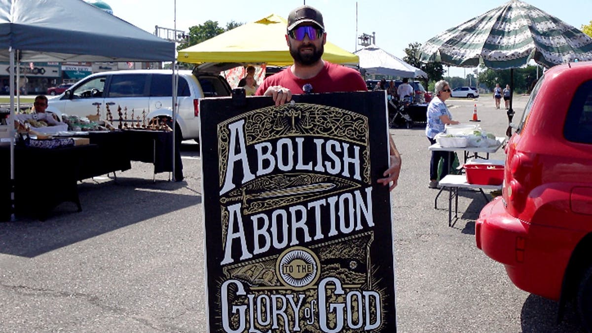 Street preacher Bryan Conwell holding anti-abortion sign.
