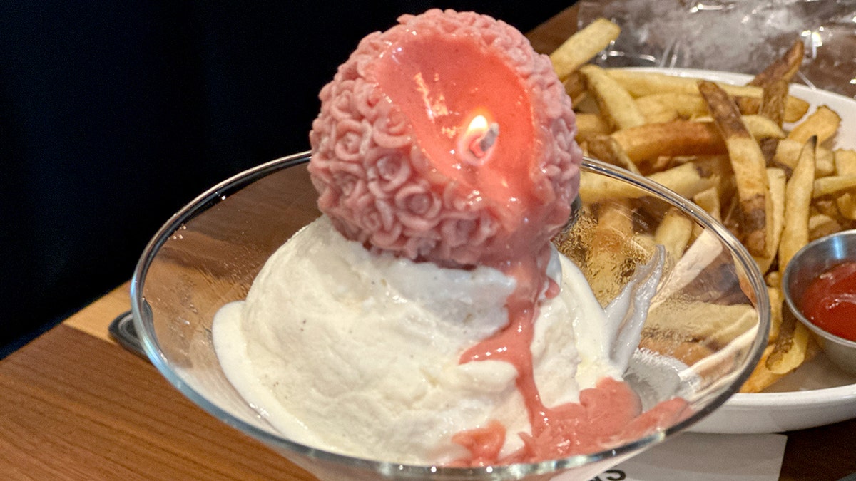 A CeraVida raspberry-flavored edible candle melts on ice cream in a martini glass.