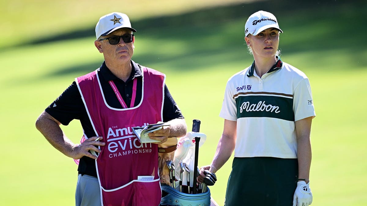 Charley Hull and caddie Adam Woodward look across the third hole during a golf tournament.