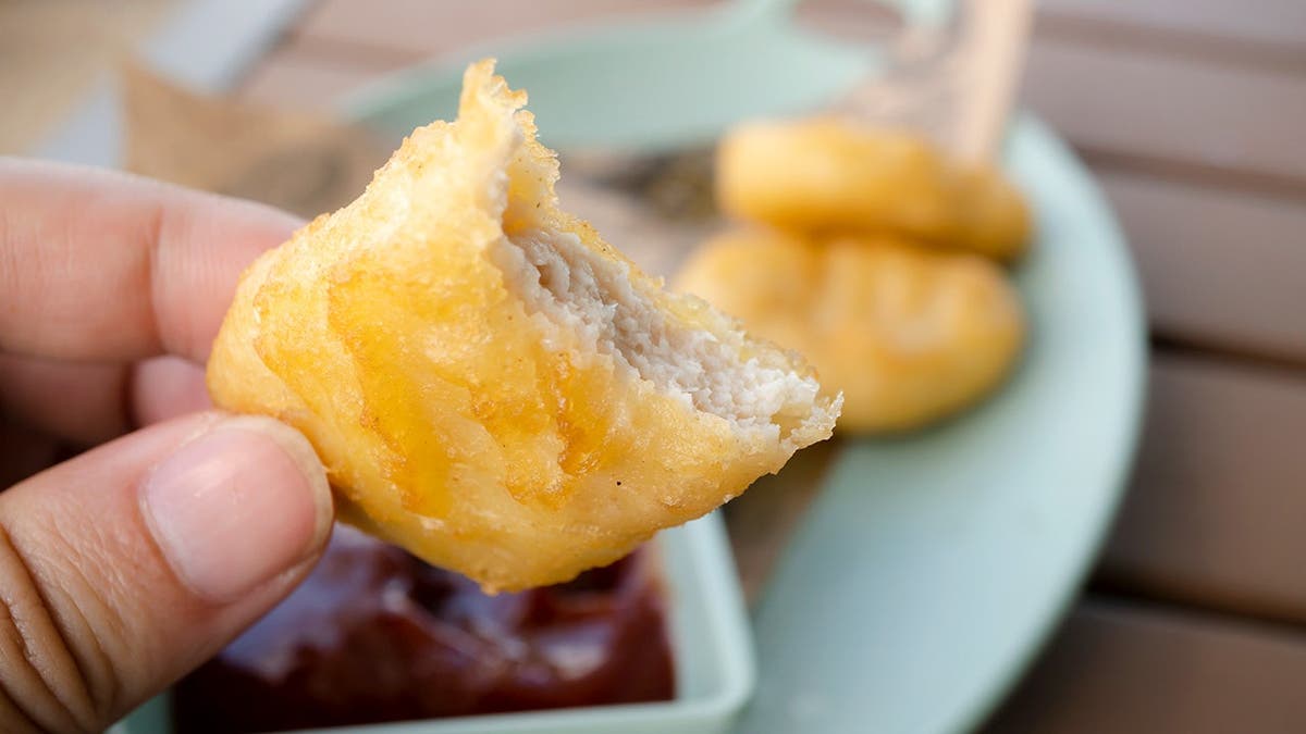 A person holds a chicken nugget.