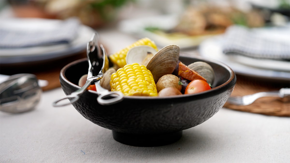 A clam bake meal prepared in a black bowl.