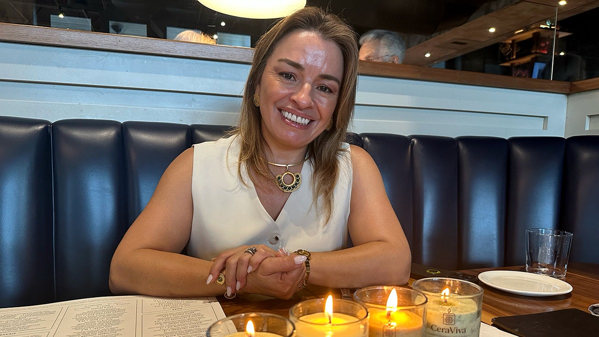Claudia Mosley smiles while seated at a restaurant booth with her CeraVida edible candles.