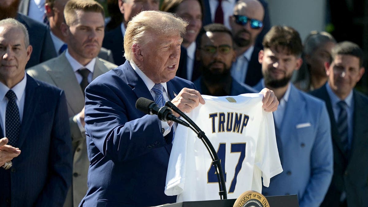 Donald Trump holds a Los Angeles Dodgers jersey with his name and number 47 during a White House ceremony.