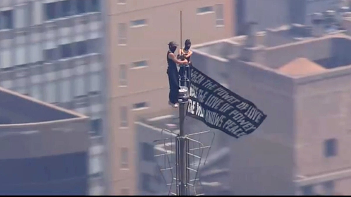 Two people holding a banner on top of the Empire State Building