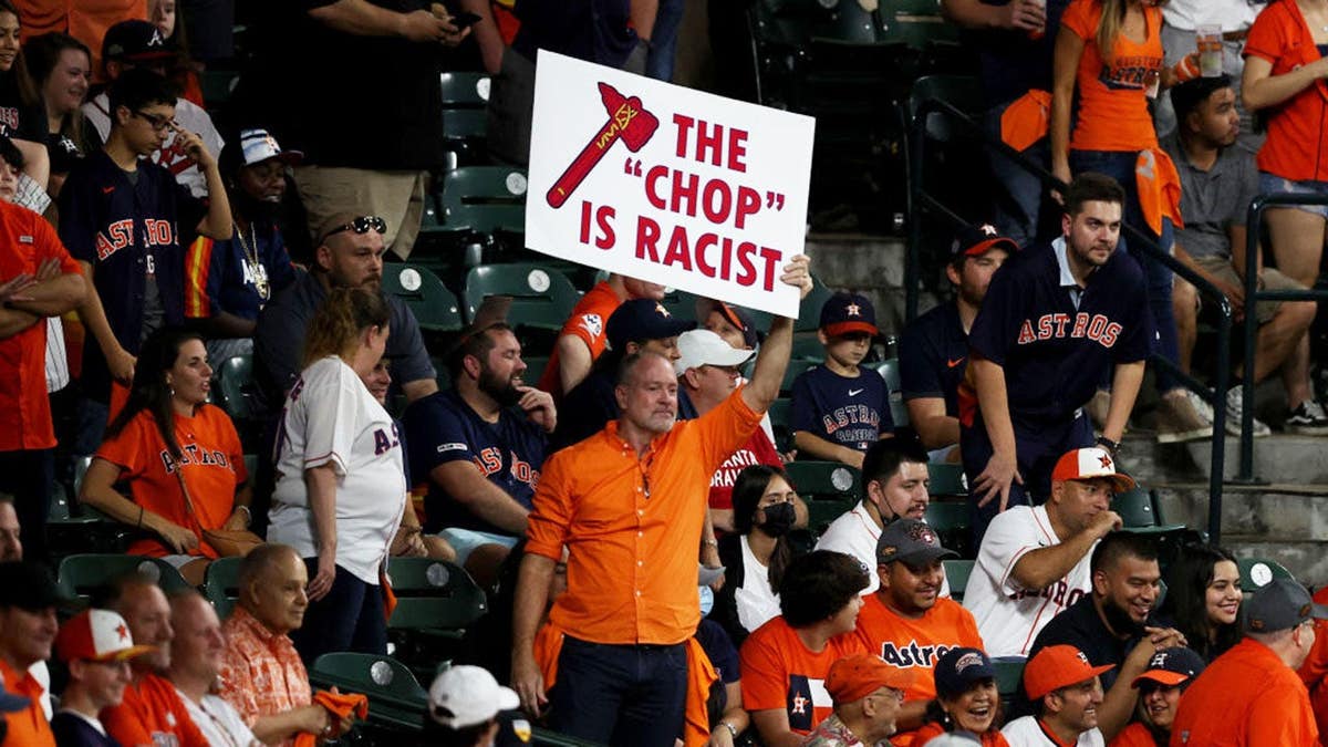 Fan holds a sign stating 'the chop is racist' during World Series game at Minute Maid Park.
