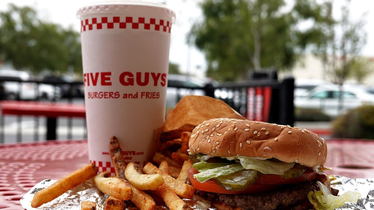 A burger, fries and a drink from Five Guys sits on a table.