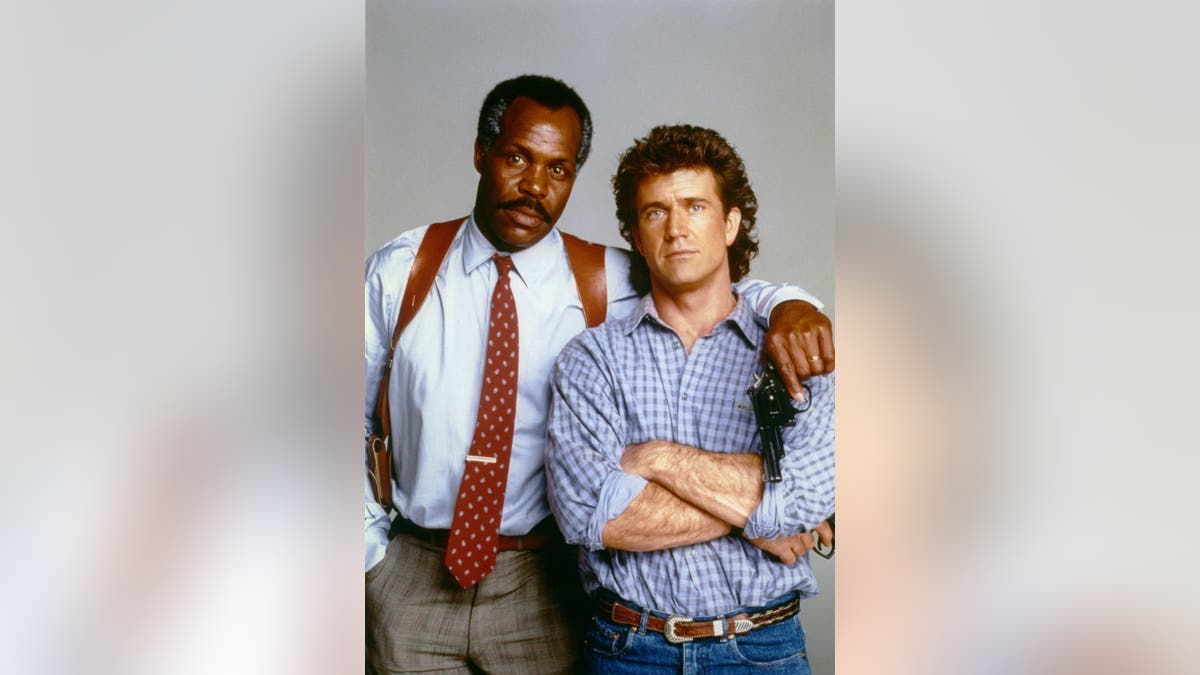 Danny Glover and Mel Gibson stand on the set of Lethal Weapon.