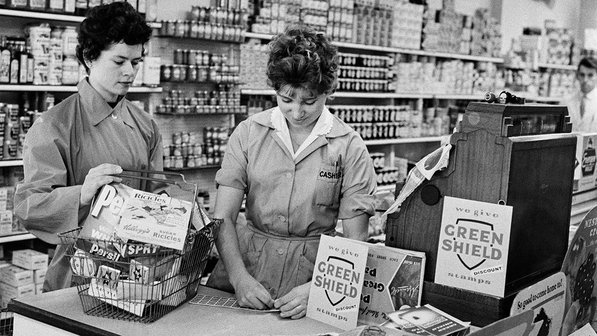 Shop assistant gives Green Shield stamps to a customer in the supermarket.