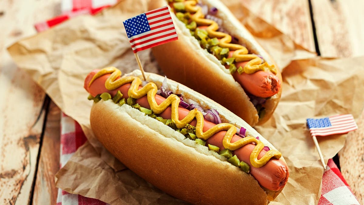Two hot dogs sit on a table.