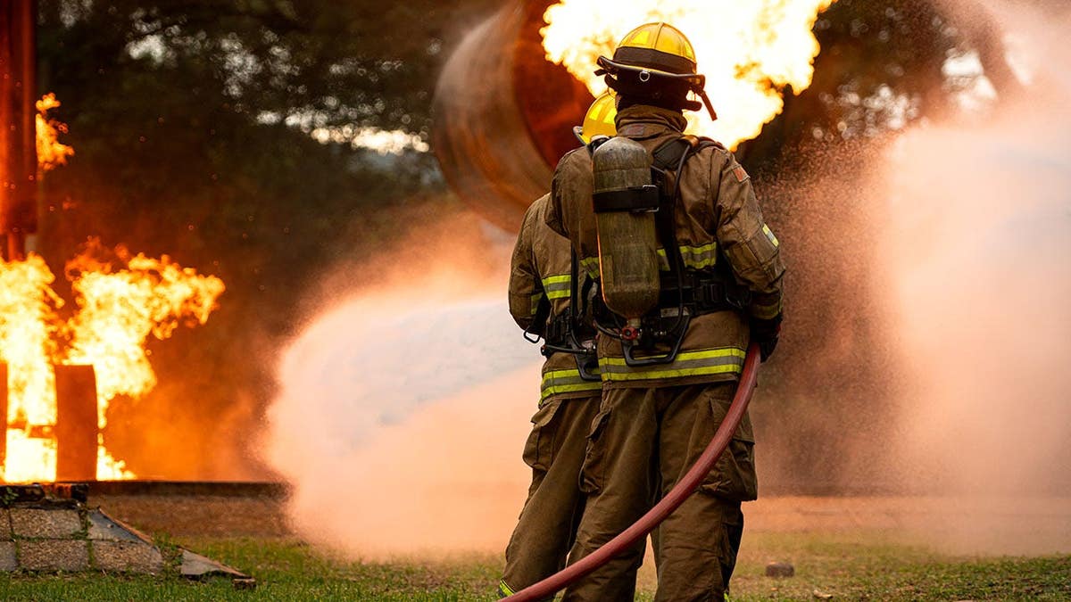 A group of firefighters uses high-pressure hoses to battle a massive blaze