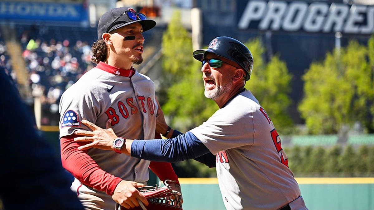 Jarren Duran yells toward a fan as José David Flores holds him back.