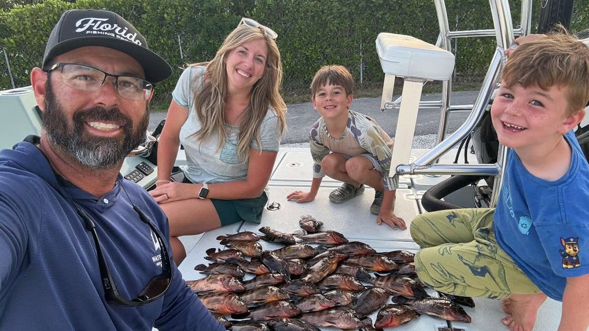 family gathers around pile of fish on boat